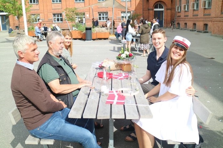 Student med familie ved bord i skolegården